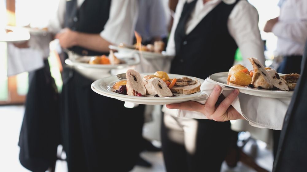 Catersource magazine | waiters carrying plates meat dish wedding | catersource 2020