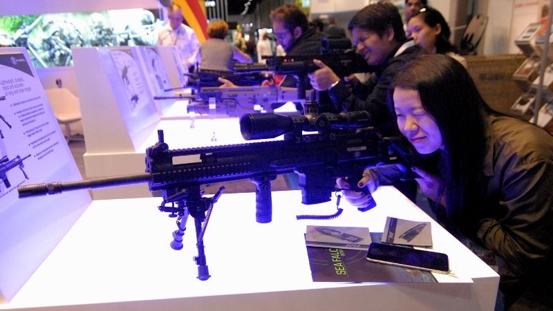asian woman checks a rifle during arms exhibition | Western Trails Gun and Knife Show 2020